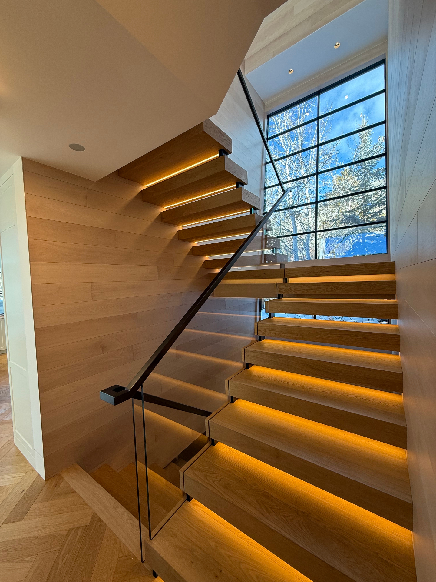 Floating white oak treads with LED lighting and blackened steel handrail