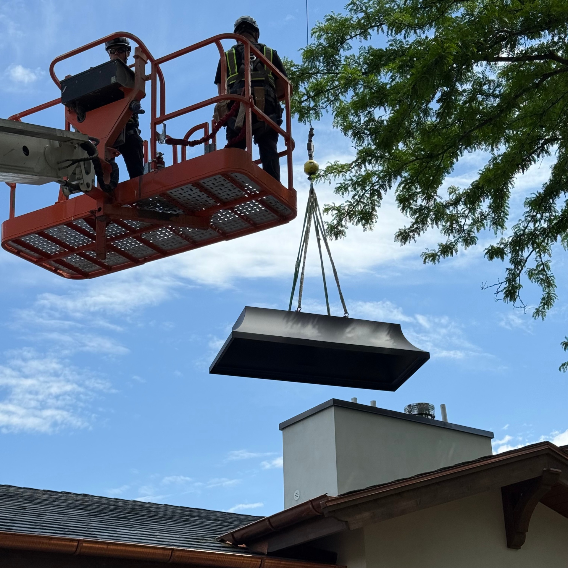 PetriCore team installing a custom chimney cap from a lift