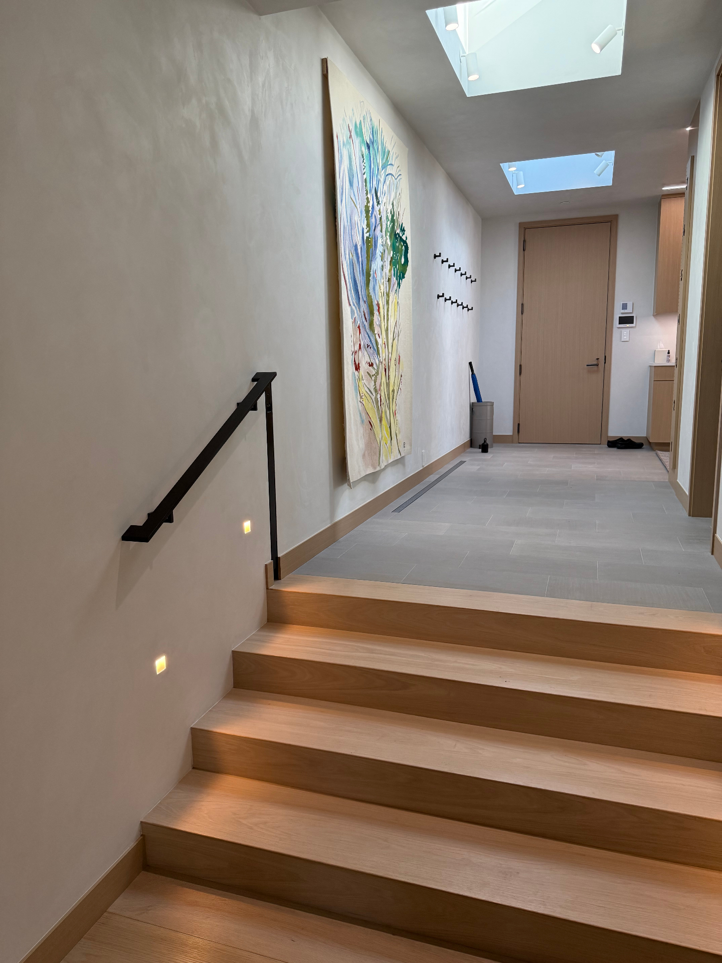Minimal blackened steel wall-mounted handrail on interior stair