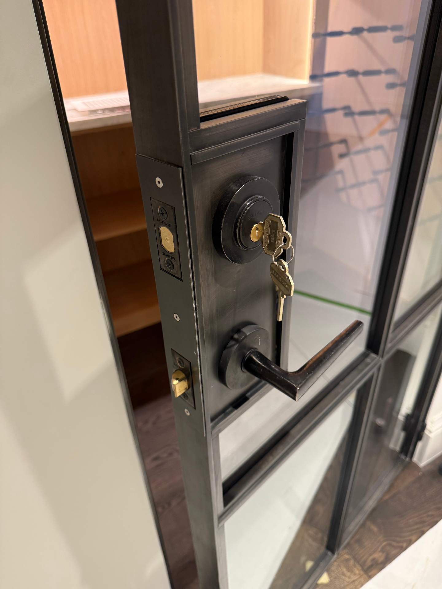 Blackened steel and glass door with hand-applied patina hardware