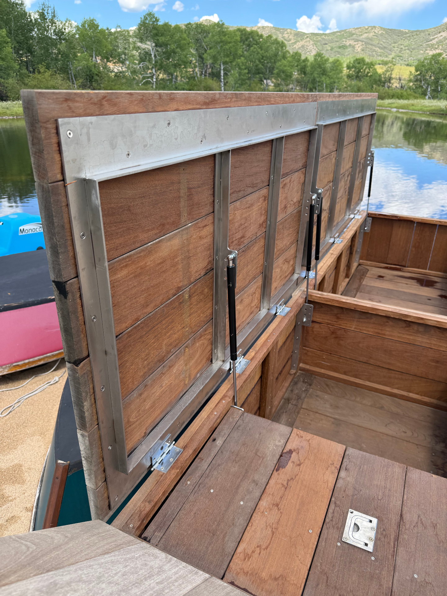 Custom stainless steel hatch frames on a lakeside wooden dock